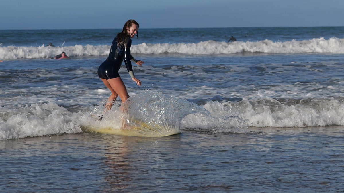 Surfer riding whitewater, the spray off her board frozen like a glass sheet